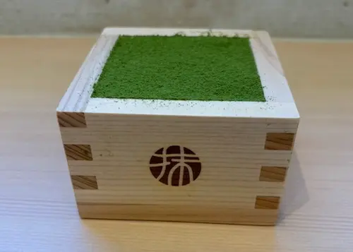 Matcha tiramisu served in a traditional masu box, a small wooden container used to measure rice or sake.