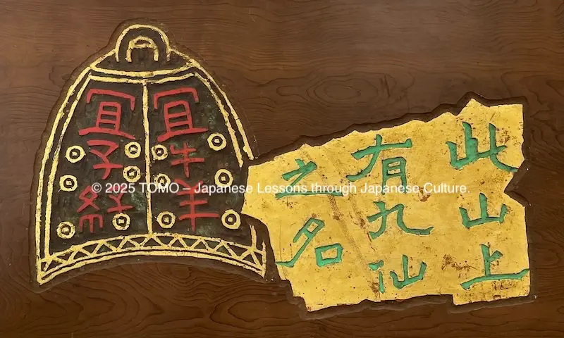 郊処 (Kōsho) Tenseki-gaku: Gold leaf wood engraving featuring green 「九仙之名」 and the red bell motif.